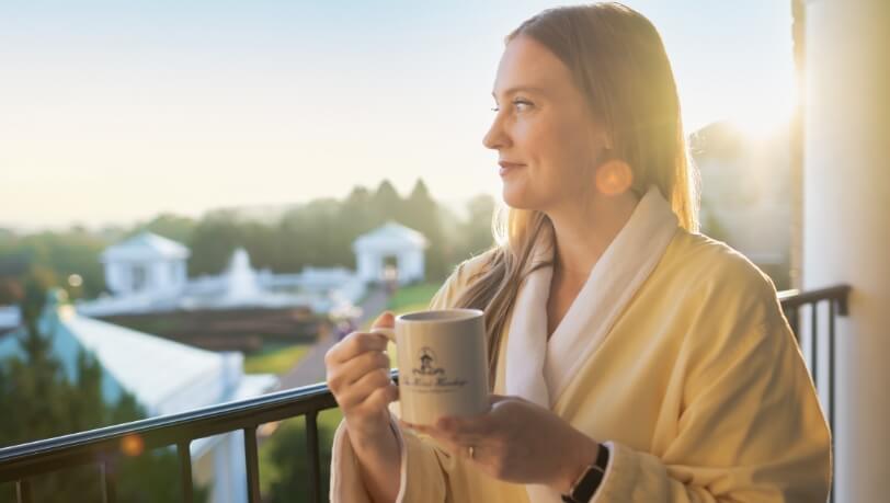 woman standing on hotel balcony sipping coffee at the spa