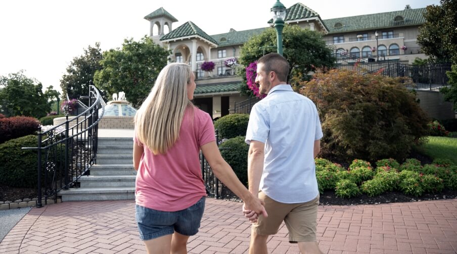 Man and woman holding hands and walking outside of The Hotel Hershey.