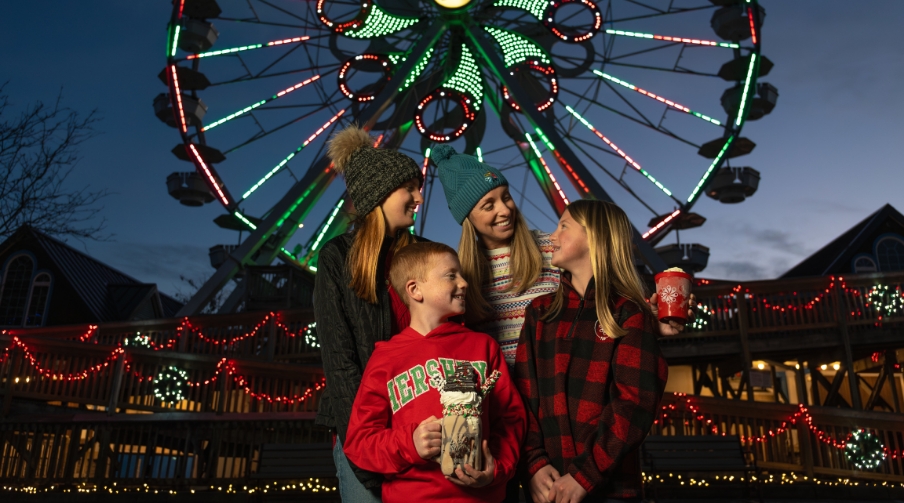 Family with three children posing in front of ferris wheel.