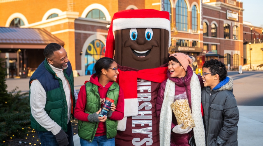 Family posing with Hershey character dressed for Christmas.